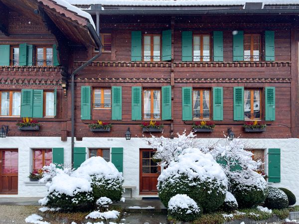 Traditional Swiss chalet in snowy Rougemont with green shutters, VD