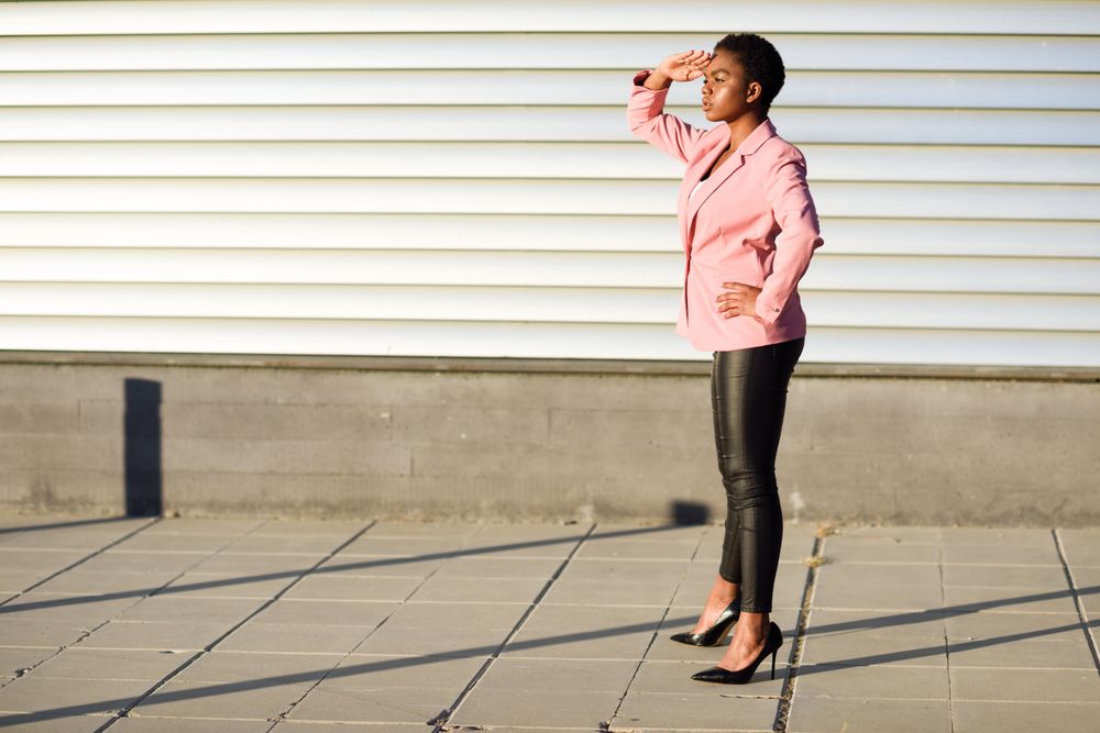 Female in modern business suit with hand protecting her eyes from the sun