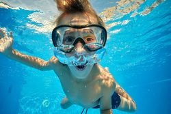 Amazed boy blowing air bubbles in pool