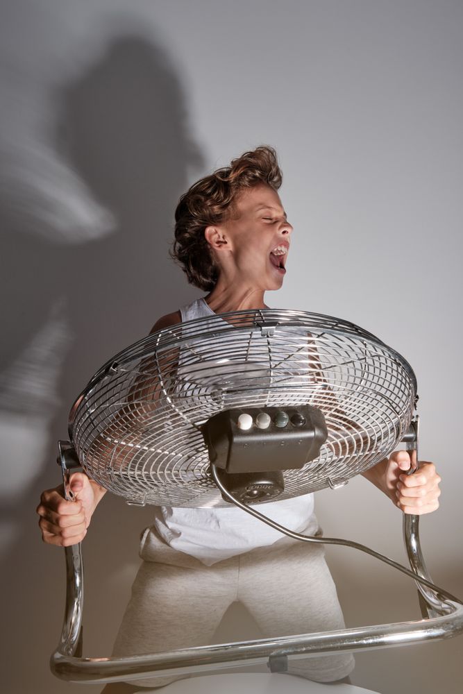 Excited boy screaming in front of blowing fan