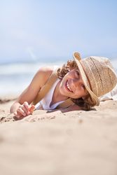 Smiling boy relaxing on sandy beach in summer