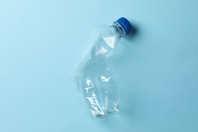 Squashed plastic water bottle on blue table