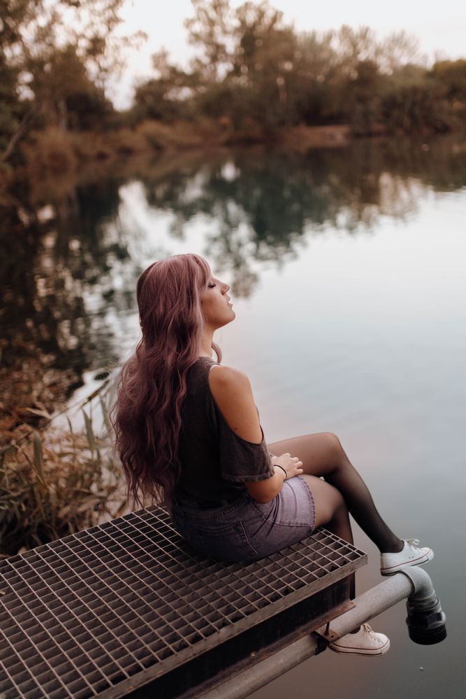 Stylish modern woman sitting on metal pier