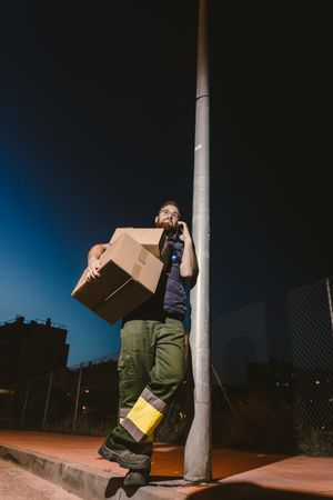 Dedicated courier phoning for delivery completion while waiting client on street in evening