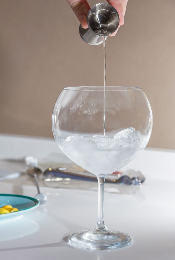 Barman pouring drink to prepare gin tonic cocktail