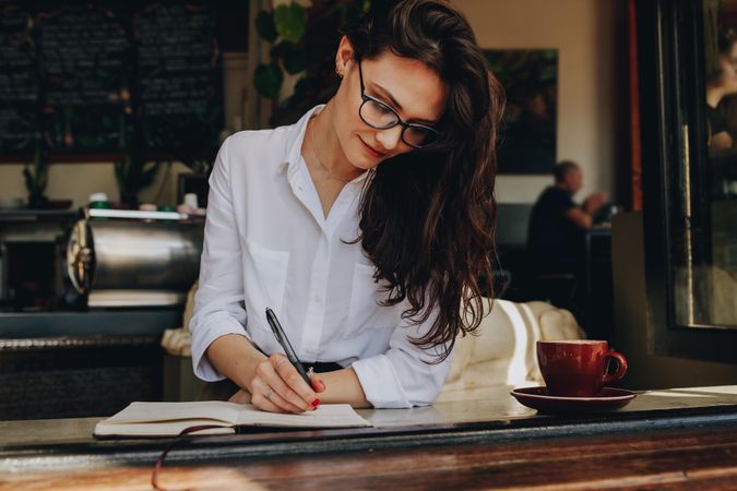 Female writing in book at coffee shop