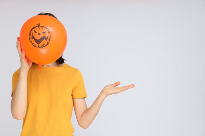 Concept of Halloween, Woman holds Halloween balloon on light background