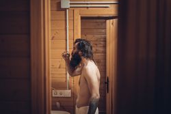 Bearded man brushing teeth in wooden house