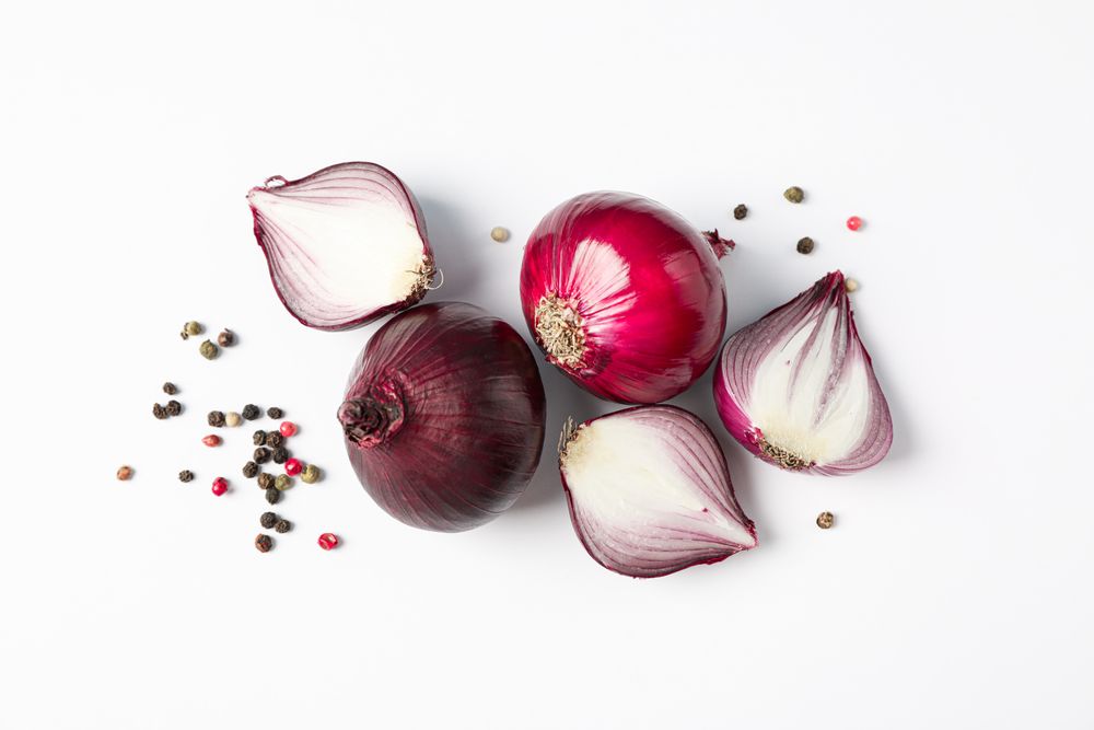 Flat lay composition with red onion and spices on plain background