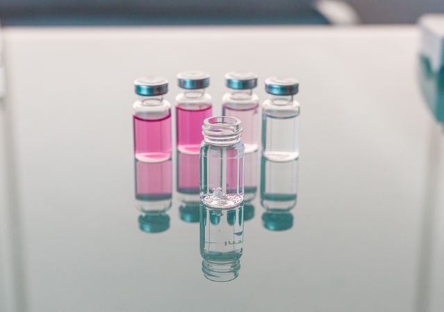 Vials with scientific samples arranged on glass table