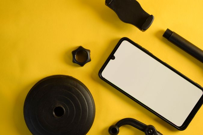 Mock up phone with accessories scattered on yellow background with space for text