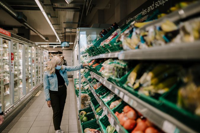 Grey haired woman choosing vegetables in the produce aisle