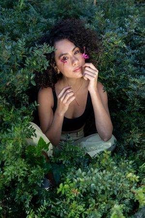 Beautiful young woman with afro hair surrounded by flowers looking at camera