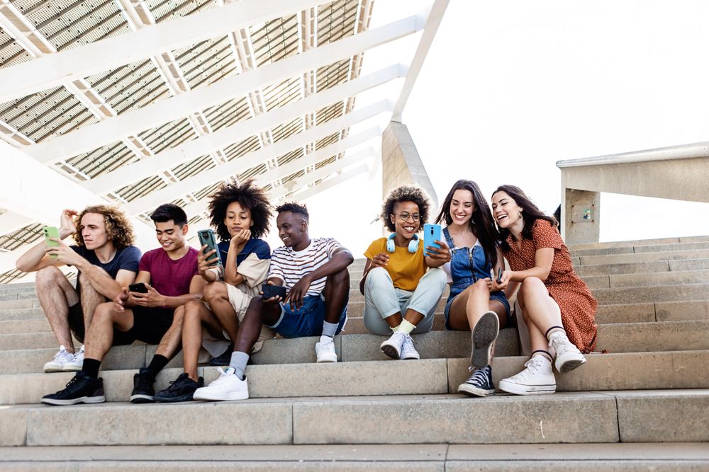 Group of diverse students using mobile phone outdoors