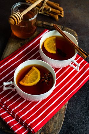 Two tea cups with lemon and star anise on red napkin