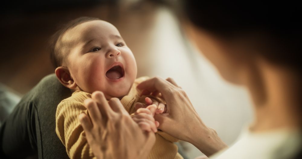Motherly Affection Concept: Portrait of a Cute Asian Baby Laughing and Enjoying a Bonding Time with Mother
