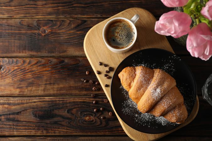 Top view of pastry, coffee, and pink flowers with copy space