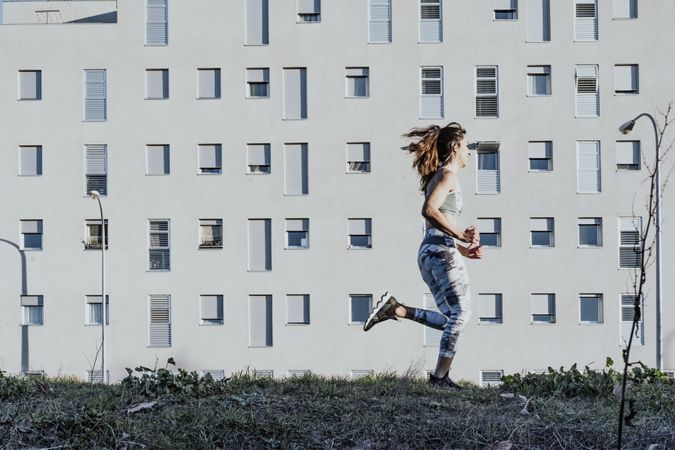Woman in sportswear running near building