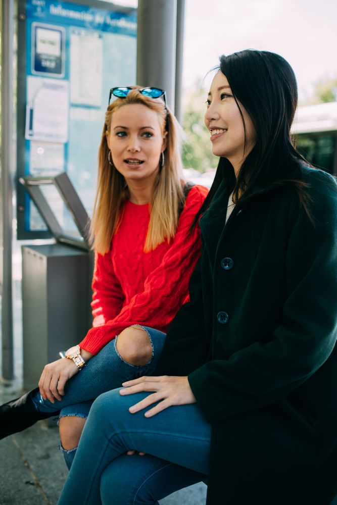 Multiethnic friends sitting on bus stop