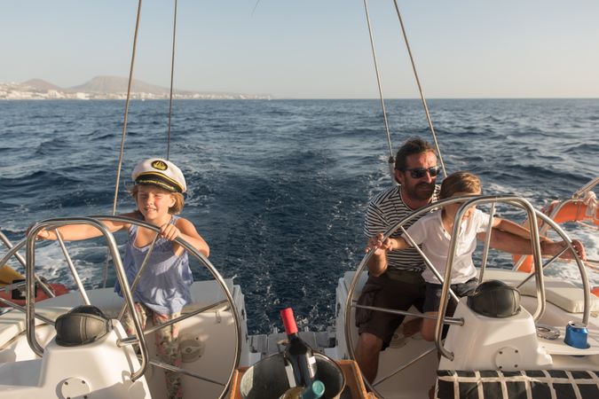 Man and boy holding steering wheel on yacht on water