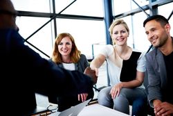 Smiling female business associates shaking hands at an informal meeting in an office