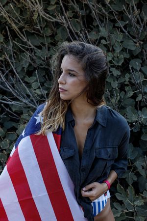 Young woman in casual clothing and American ensign enjoying in nature