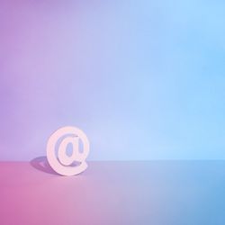 Internet “at” symbol on a gradient pink to blue background