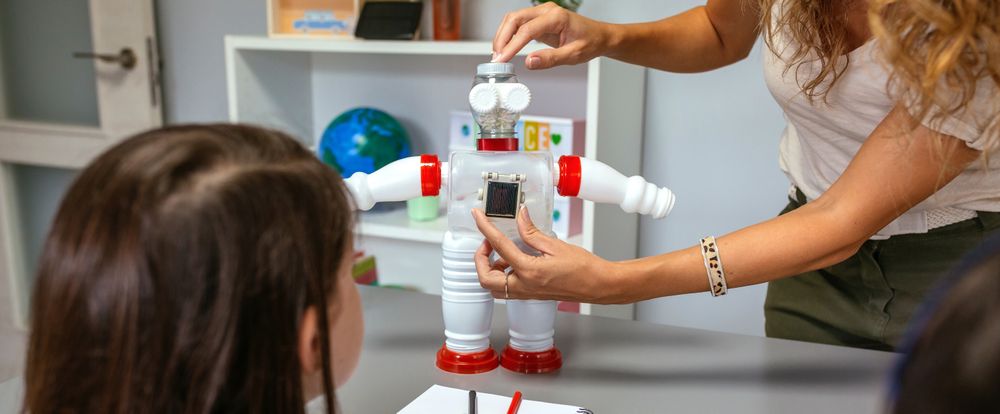 Teacher in a robotics class explaining how connect solar panel on recycled toy robot