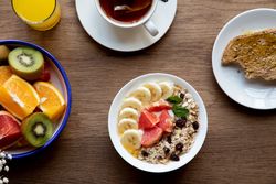 Juice and plate with granola and fruits on table