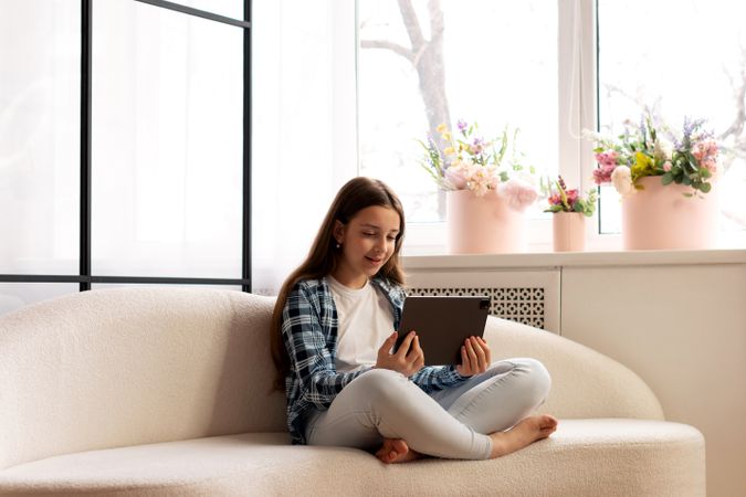 Girl smiling during video call on tablet sitting indoors.
