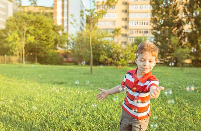 Happy boy playing with soap bubbles in the park