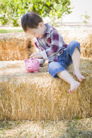 Cute Young Boy Putting Coins Into Piggy Bank