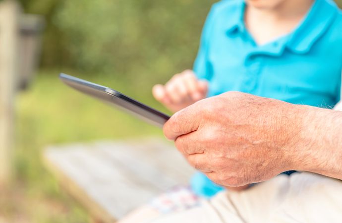 Grandfather hands using tablet with grandchild