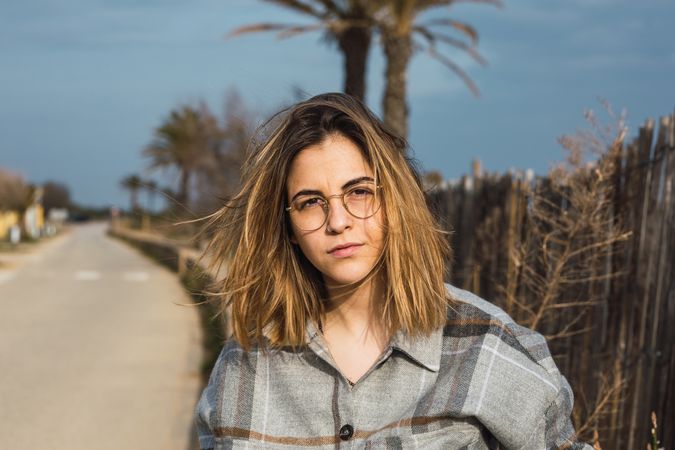 Trendy young female millennial resting on stone border at roadside