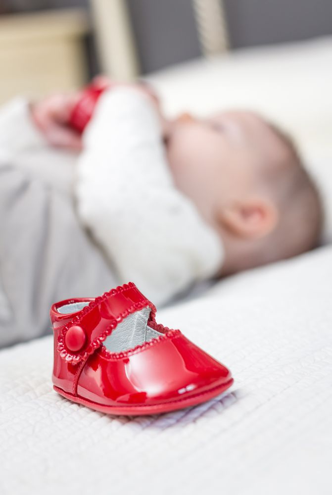 Baby red shoes and babe playing on the background