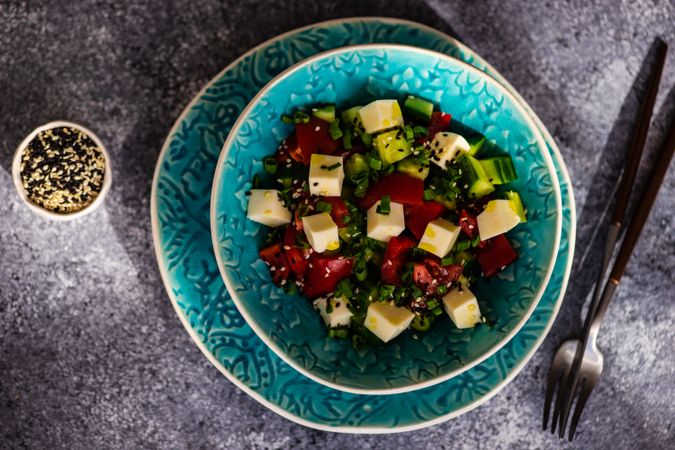 Top view of Greek salad with fresh vegetables, cubed cheese served with sesame seeds