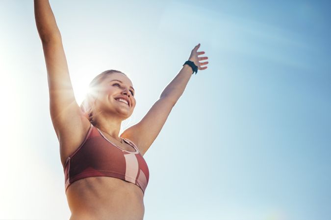 Smiling fitness woman doing workout raising her arms