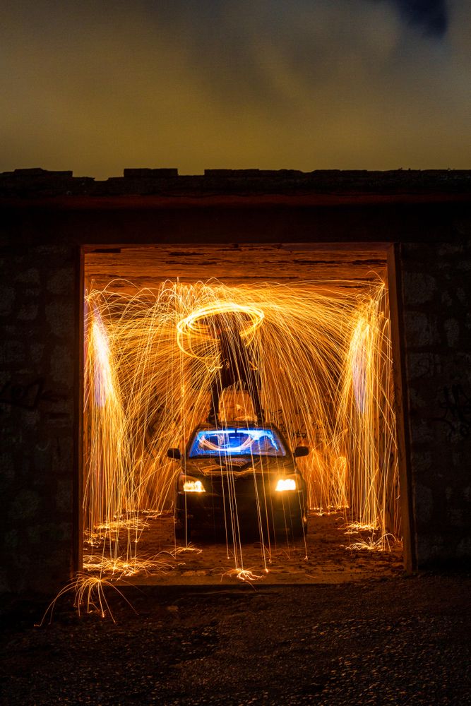 Person with burning round on car in garage in darkness