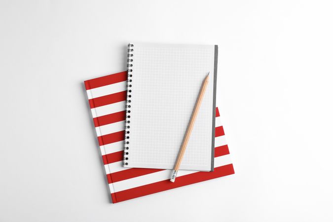 Copybooks and pencil on blank background, top view