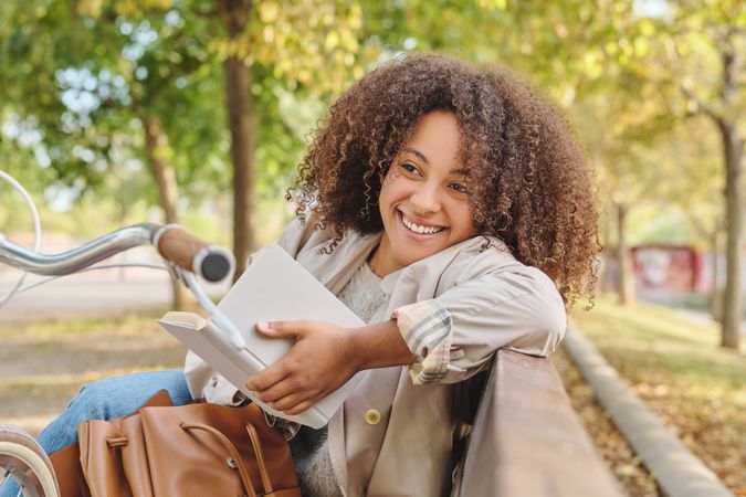 Smiling Black woman reading book in park