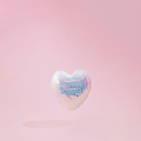Iridescent sequins heart on pink background
