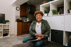Smiling older Black woman sitting on sofa using tablet