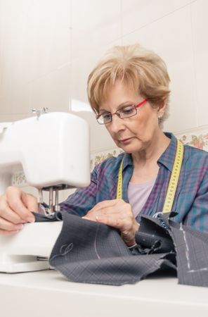 Mature seamstress woman working on sewing machine