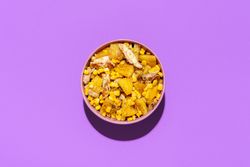 Pineapple chicken salad bowl, above view on a purple background