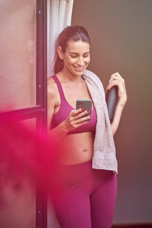 Smiling fit female browsing mobile phone in studio