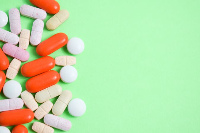 Top view of pills and vitamins on green table with copy space