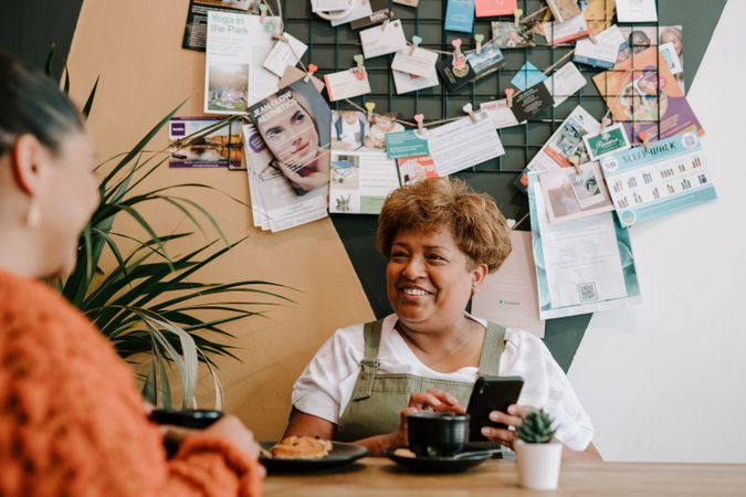 Older Black woman with smart phone talking with daughter at cafe