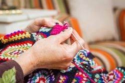 Hands of woman knitting a vintage wool quilt