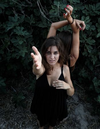 Young women posing near green bush