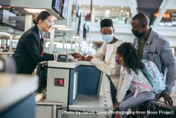 Travelers at check-in counter with airlines staff during pandemic 49PjL5